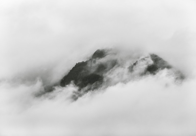 misty mountains peek through clouds on an overcast day on the west coast, veiled 4k