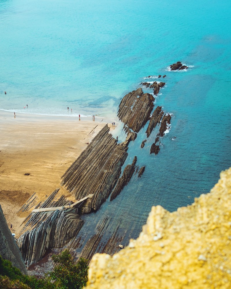 a tourist spot with unique rock formations leading to the ocean, _rocks of izturun 4k