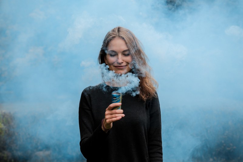 smiling girl engulfed in the blue smoke holding smoke flare in moscow, smiling girl holding a blue smoke flare 4k