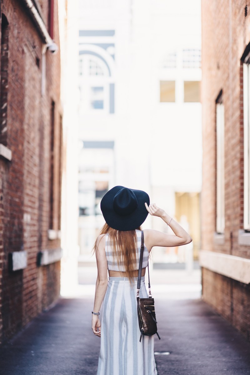a woman in a hat walks away from the camera in an alleyway in perth, woman in alleyway in perth 4k