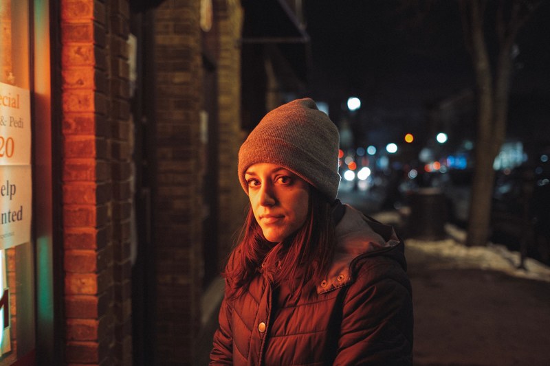 a woman in a knit cap and coat stands on a snowy sidewalk in bayonne, the perfect portrait 4k