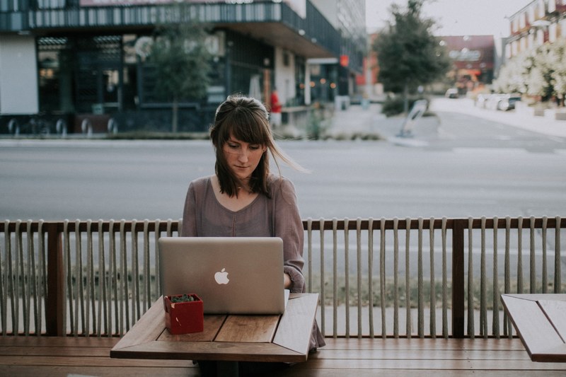 a woman working on a laptop outside a coffee store, office working 4k