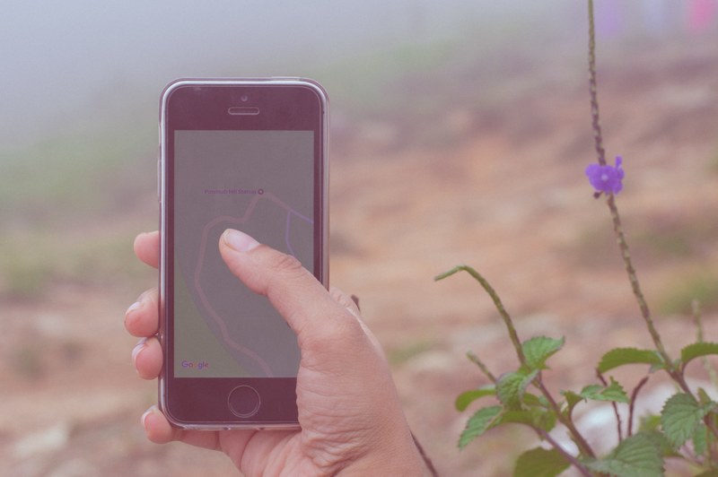 a persons hand holding an iphone with a map app outdoors, navigating in the wilderness 4k