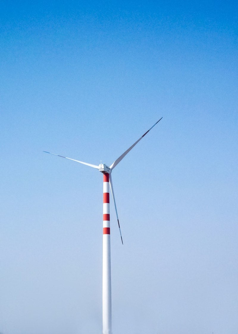 lone wind turbine against a clear blue sky, powering through the wind 4k