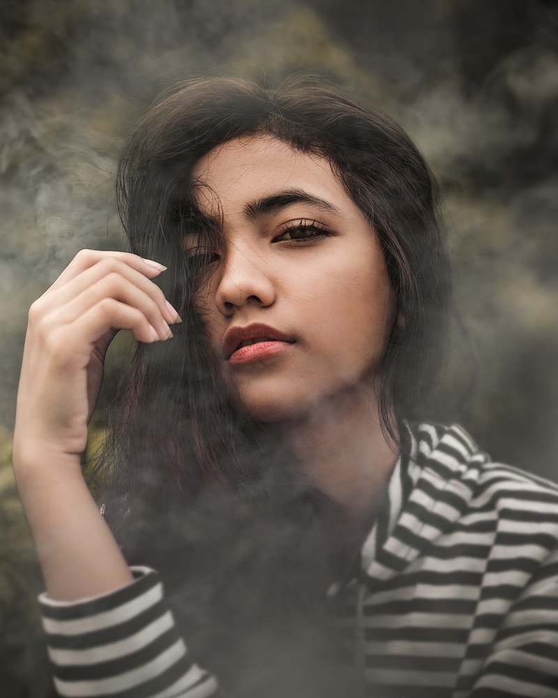 young woman with long brown hair looks tired, serious woman in striped shirt 4k