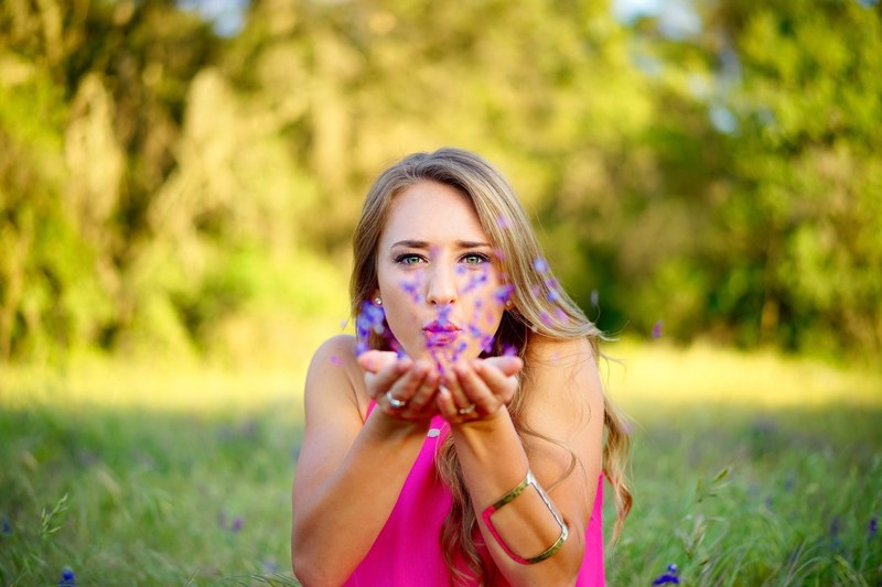 a young woman blowing at small flower petals in her hands, blowing at flower petals 4k