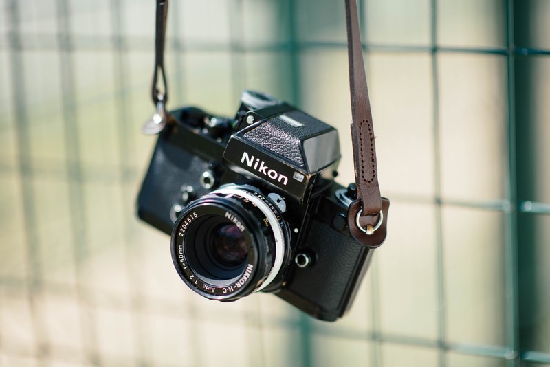 nikon vintage camera with a leather strap hanging from a metal fence, nikon vintage camera 4k