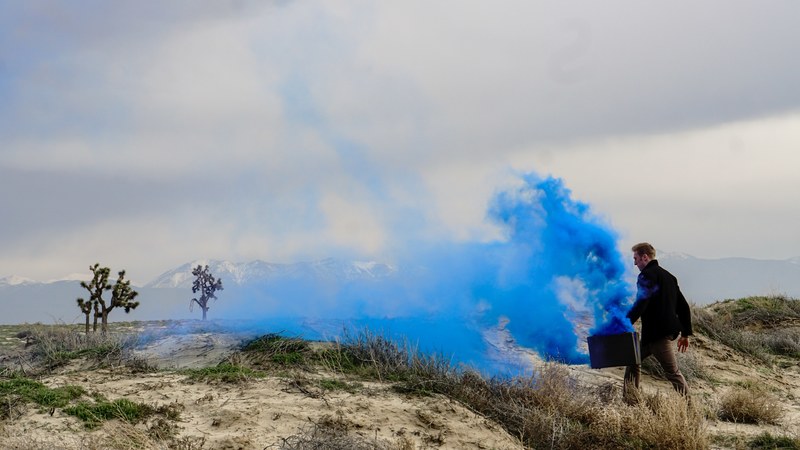 thick blue smoke coming out of a suitcase carried by a man walking through the wilderness, blue smoke in a suitcase 4k