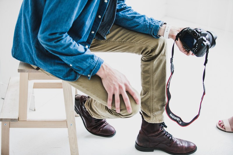 a man wearing a denim shirt and khakis taking a photo with a canon camera of a woman with sandals and red toenails, the creative mind 4k