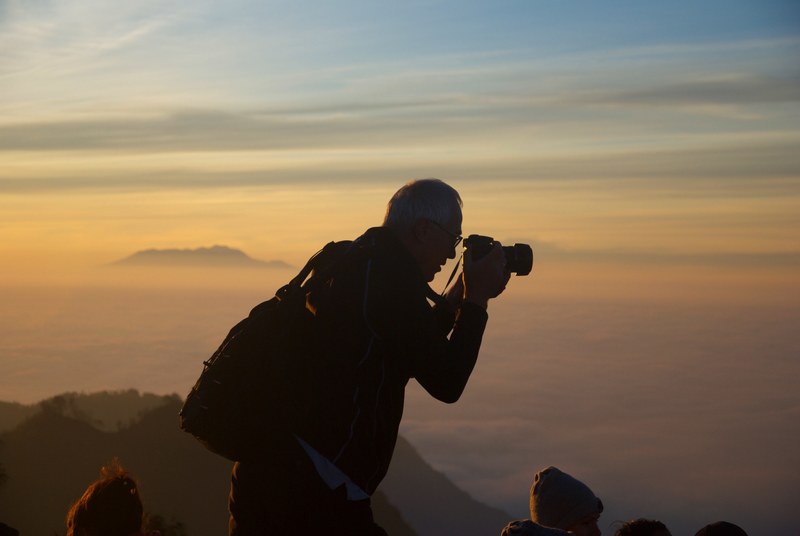 a silhouette of a man taking a photo while on top of a mountain, mountaintop photo 4k