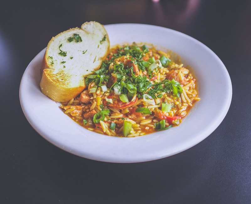 rice pasta dish garnished with green onions and parsley with a slice of garlic bread served in a ceramic bowl, foooood 4k