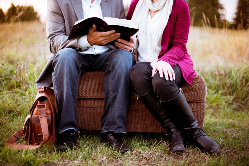 a married couple sitting on an ottoman outdoors he is reading a book, _man reading book on ottoman 4k
