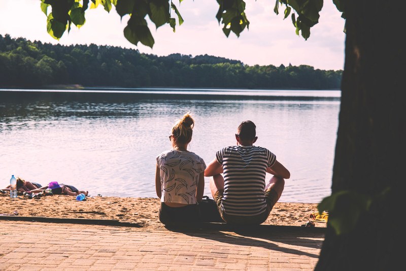 summer day at olsztyn beach features couple sitting and 2 females lying in the sand, vacation at olsztyn beach 4k