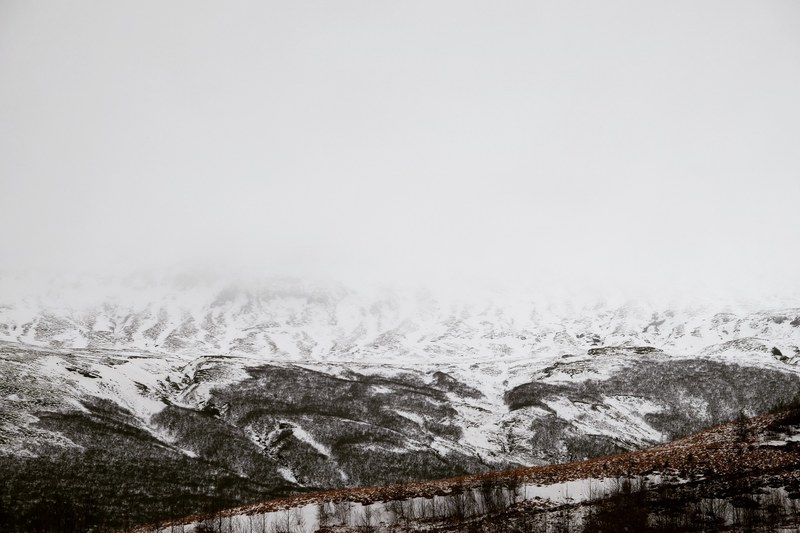 snow covers a mountainscape on a misty morning in iceland, snow capped icelandic mountains 4k