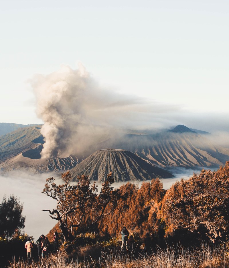 several people on a mountain slope with a cloud of smoke rising up from a volcano crater in the background, treasure from java 4k