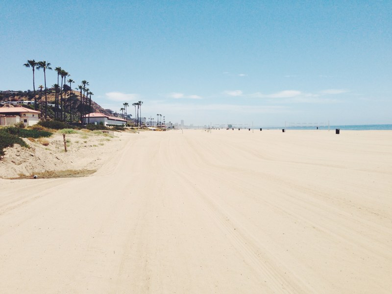 big sandy beach with volleyball nets by the houses and palm trees, sandy beach 4k
