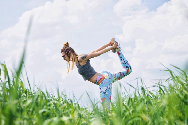 a woman wearing funky leggings doing yoga on the grass in karczewski, yoga time 4k