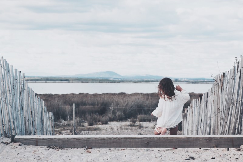 child walking by wooden fences on an overcast day near the coast at villeneuve ls maguelone, between pond and sea 4k