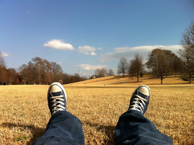 a person wearing jeans and converse relaxing on grass in a park, park relaxing time 4k