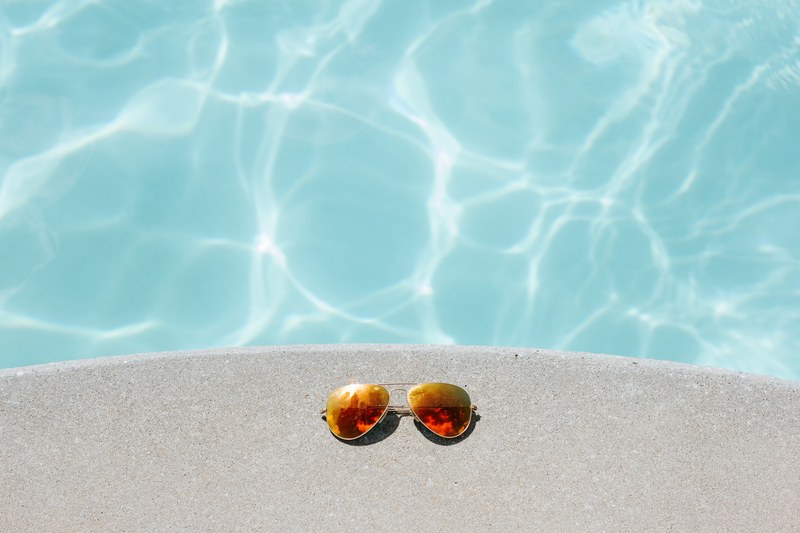 a pair of sunglasses left on a concrete ledge over clear water, reflective sunglasses 4k