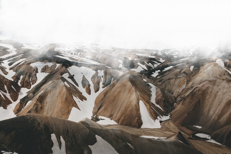 icelandic mountain range with spots of snow sit below a foggy sky, mountain under mist 4k