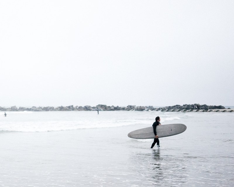 a person walking back to the beach while carrying his water board, _waterboarder walking 4k