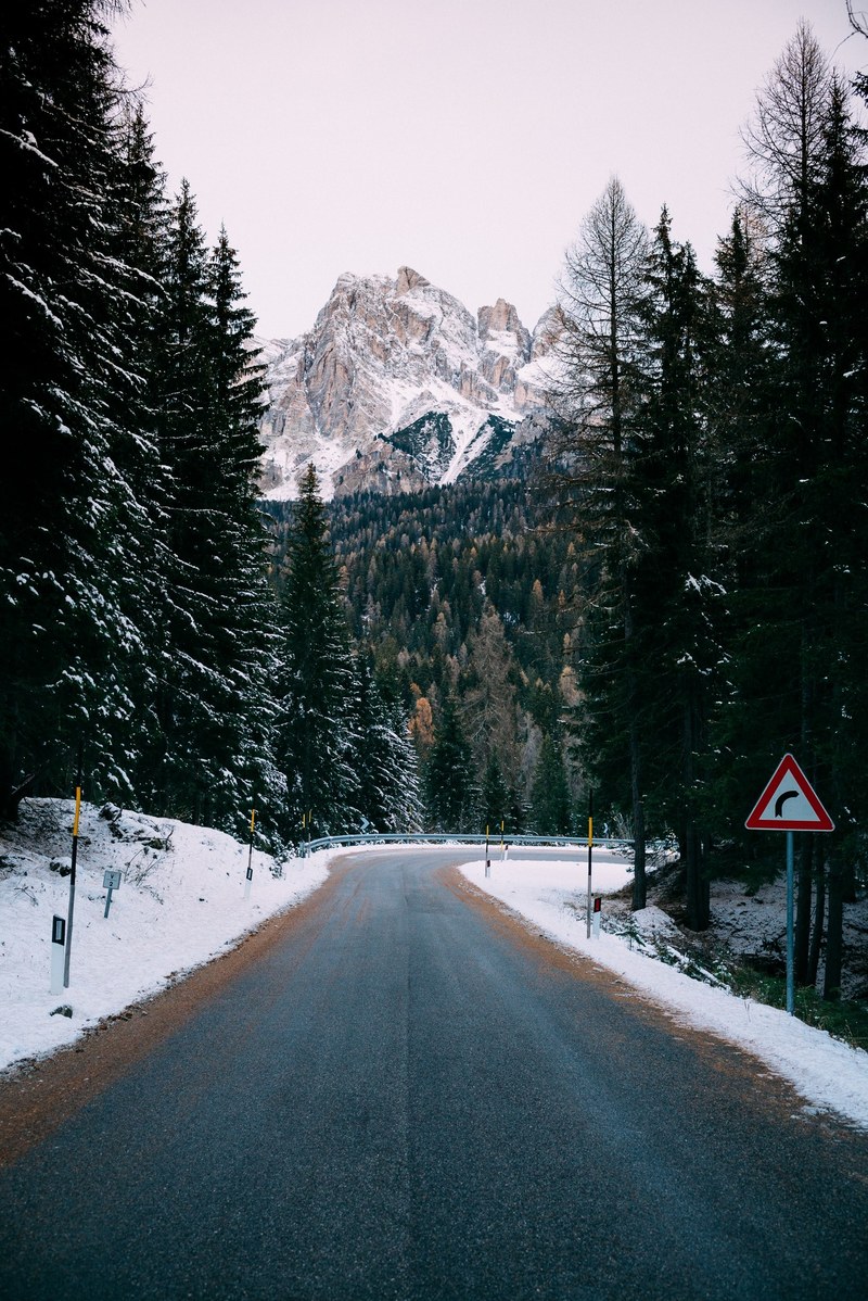 a curve in an empty road on a snowy day in the dolomites, somewhere in the dolomites 4k