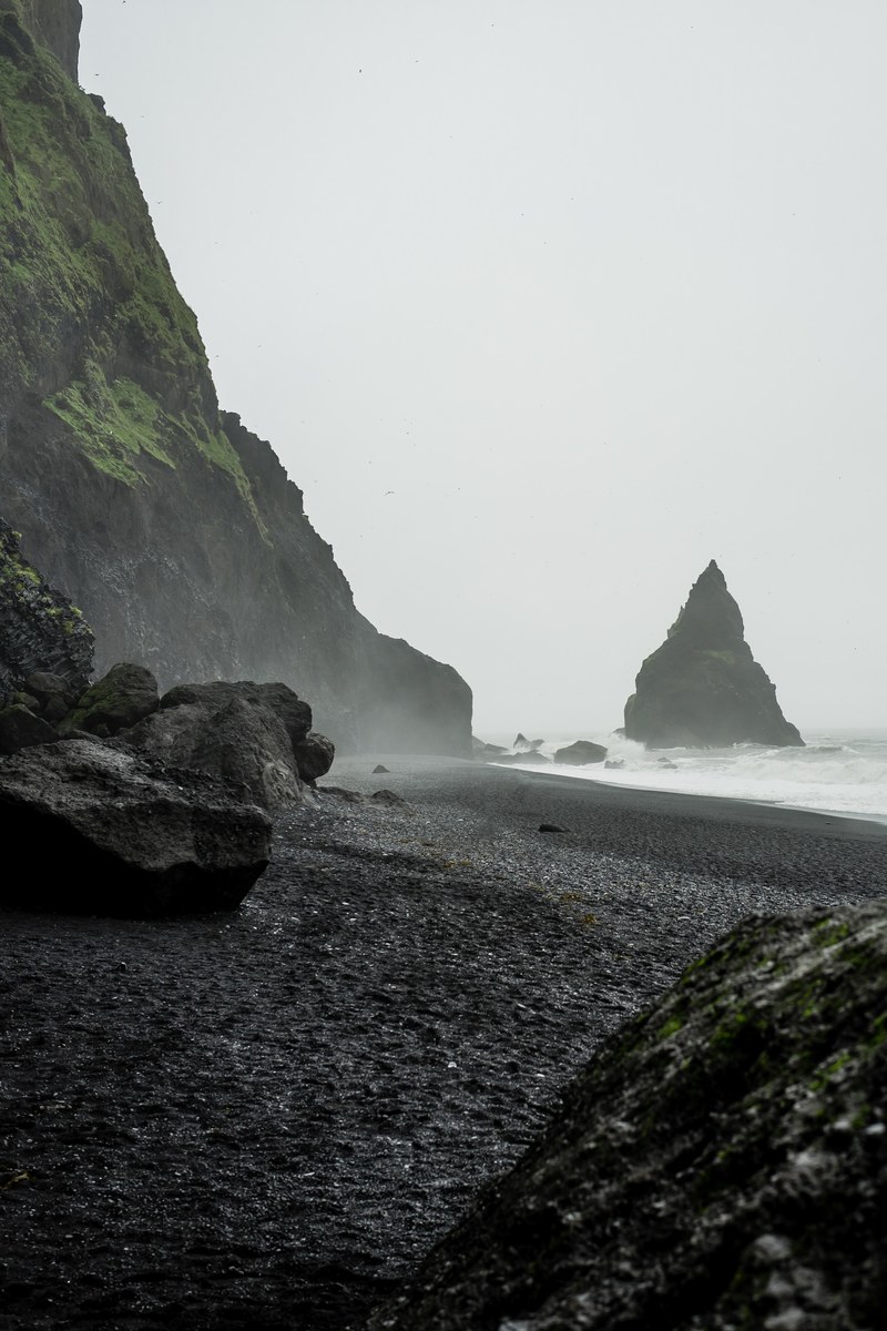 rough ocean washing on the rocky black sand shore, shore 4k