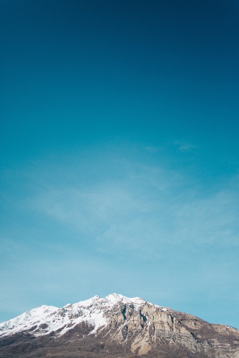snow melting off tip of mountain with open blue sky behind in texas, snowy mountain in front of blue sky 4k