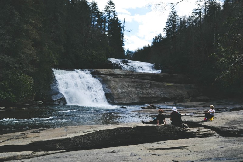small waterfall and river with evergreen trees and hiker people in spring north carolina, waterfall spring carolina 4k