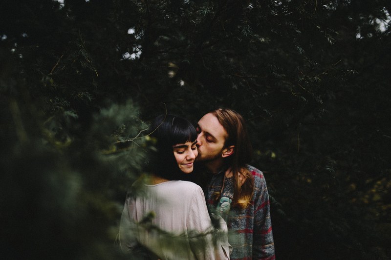 a young man with long hair kisses a young woman on the cheek in a forest, forest kiss 4k