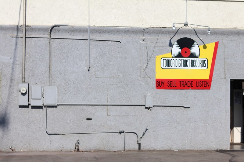 a gray wall with a tower district records record store sign, at the entrance to the record store 4k