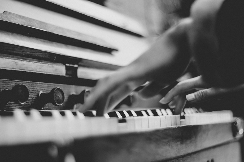 a low angle black and white shot of a person playing the piano, pianist hands in black and white 4k