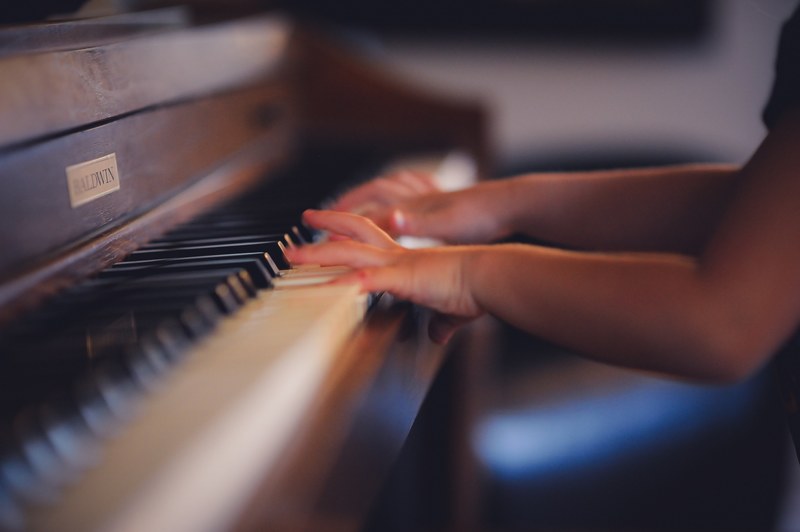 a blurry shot of a child playing the piano, young pianist 4k