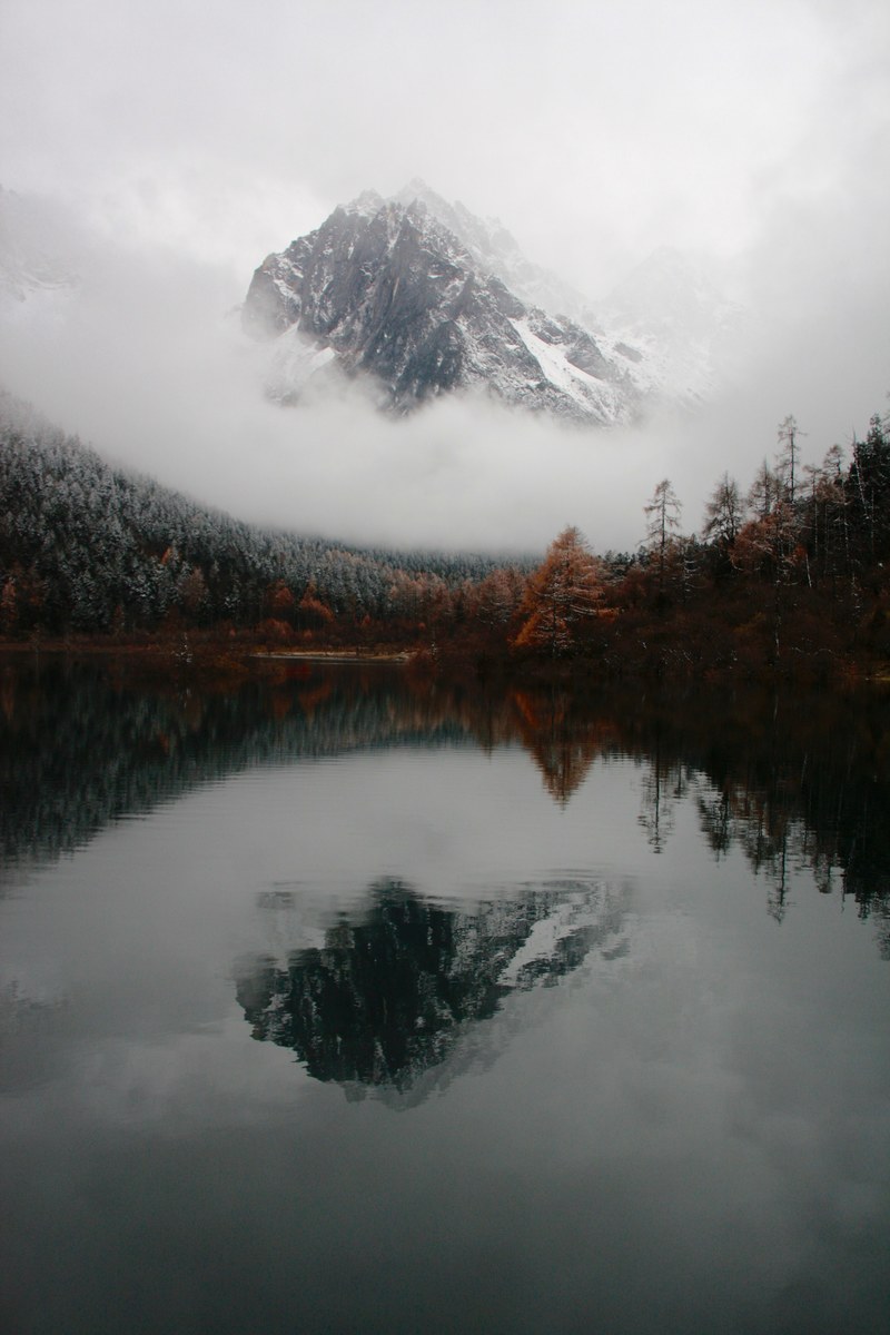 mountain peak reflects in calm waters surrounded by autumnal trees, chinas mist mountain 4k