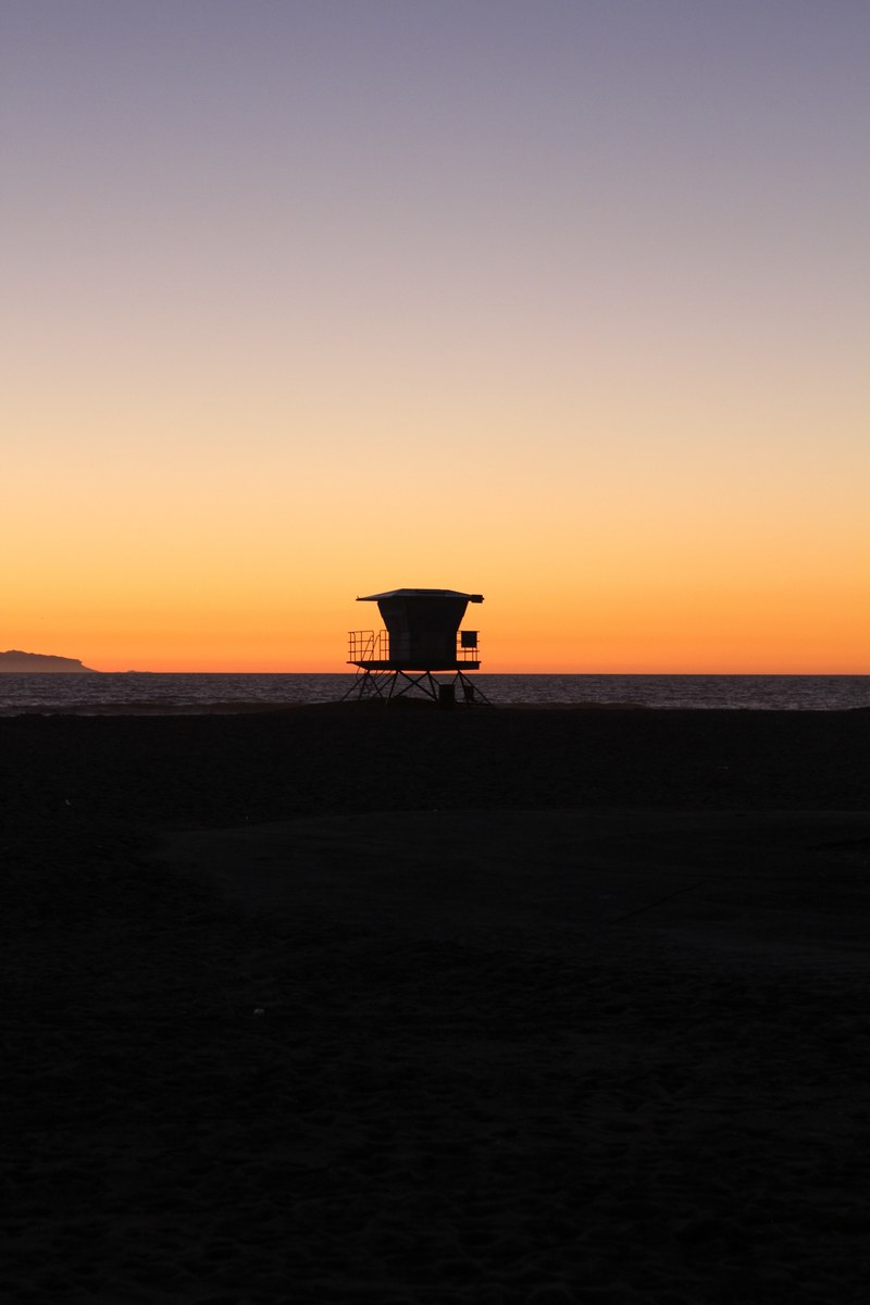 a silhouette of a lifeguard station on a deserted huntington beach at sunset, lifeguard station at huntington beach 4k