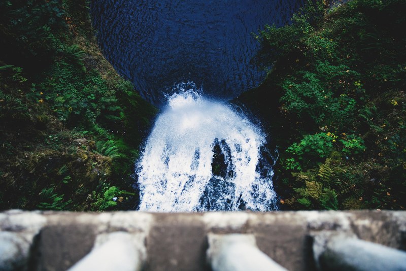 aerial view of gushing waterfall surrounded by trees underneath bridge at multnomah falls, gushing waterfall 4k