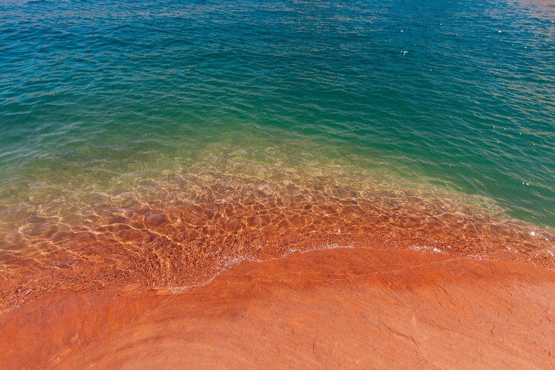 drone view of the ocean washing on the red sand shore at lake powell, red sand shore 4k