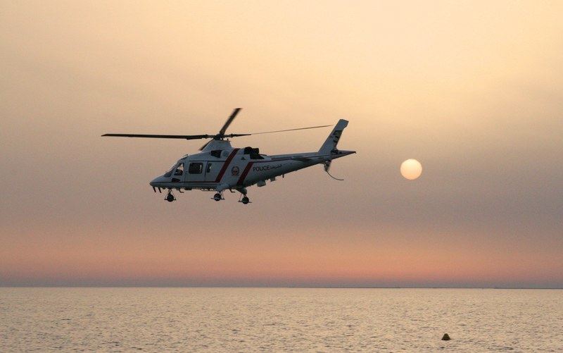 a helicopter flying over the water during sunset, _police helicopter at sunset 4k