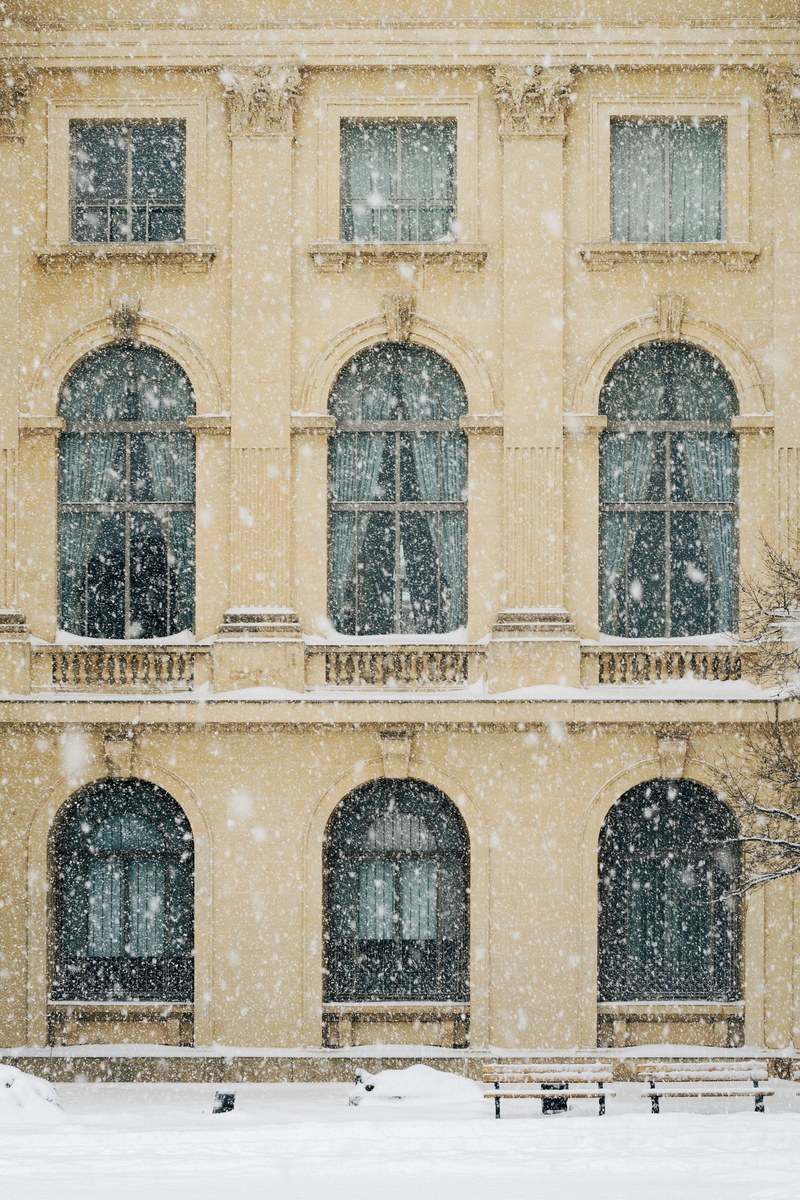 snow blowing in front of an old building in bucharest during the winter, snowing in bucharest 4k