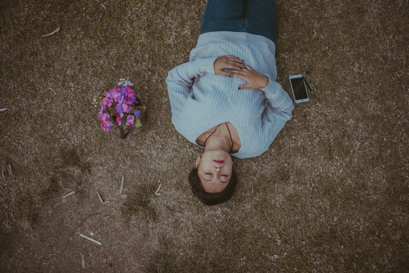 a woman lying on the ground with her eyes closed next to flowers and an iphone, suicide 4k