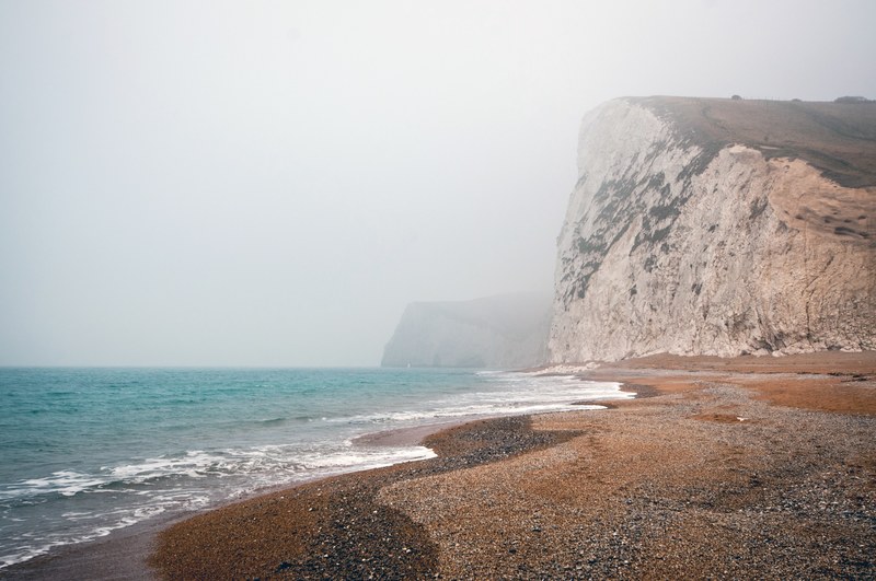bluffs line the seashore of a foggy ocean beach, cloudy coastline 4k
