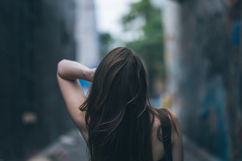 a woman with long hair faces away from the camera against a blurry background, long haired woman facing away 4k