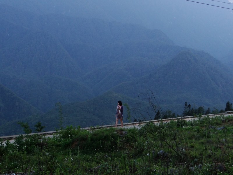 a dark haired woman walking across a path with lush undulating hills behind her, a walk over the green hills 4k