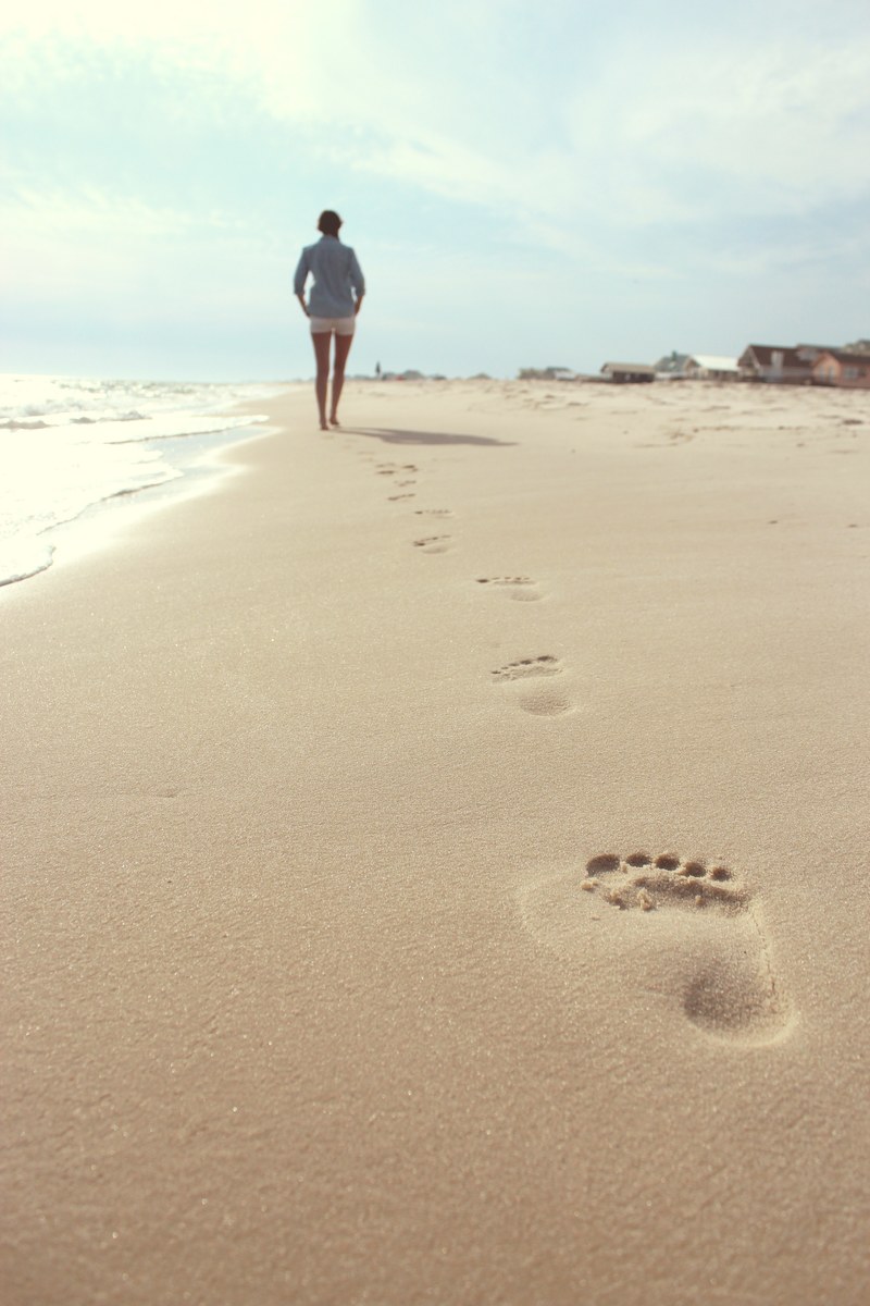 footsteps of a woman walking on a sand beach, one foot in front of the other 4k