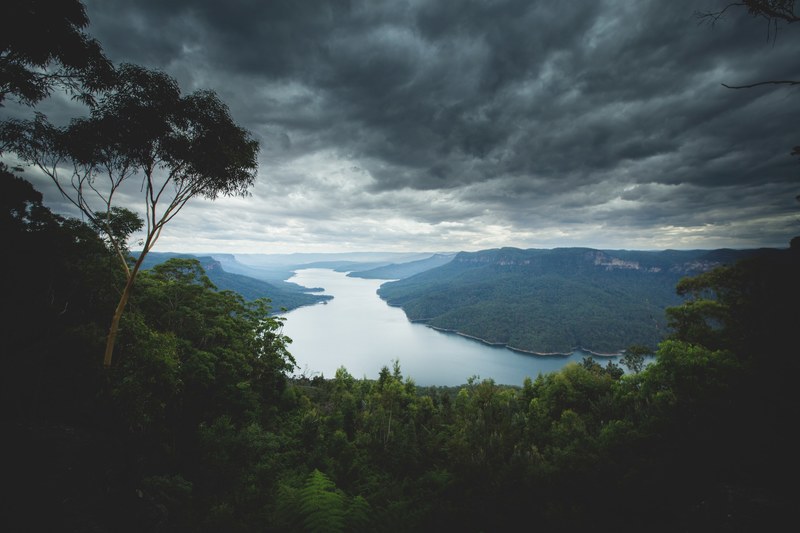 a lake in the blue mountains under overcast sky, gray clouds over a lake 4k