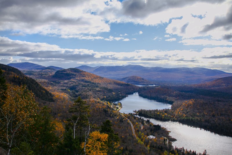 a river flowing between hills covered with autumn foliage, autumn hills in mont tremblant 4k