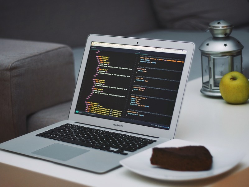 open laptop on coffee table displaying coding beside chocolate cake in living room with couch, laptop coding cake interior 4k