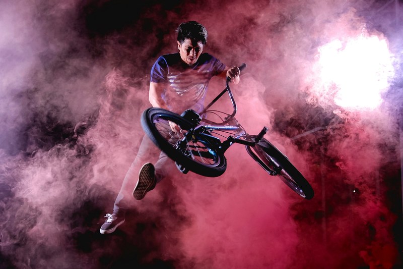 a man does a trick on a bike surrounded by purple and pink fog, bike trick in the fog 4k