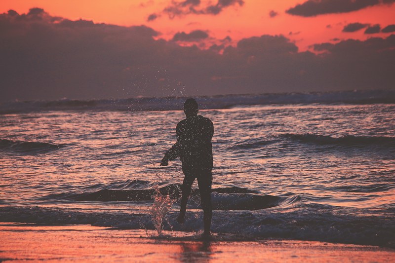 person standing on a beach splashing after sunset in asilah, splash life 4k